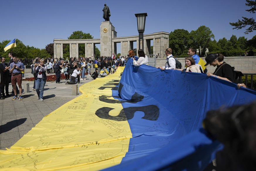 People display a huge Ukrainian nationl flag at the Soviet War Memorial at the district Tiergarten during commemorations to celebrate the end of World War II 77 years ago, in Berlin, Germany, Sunday,  ...