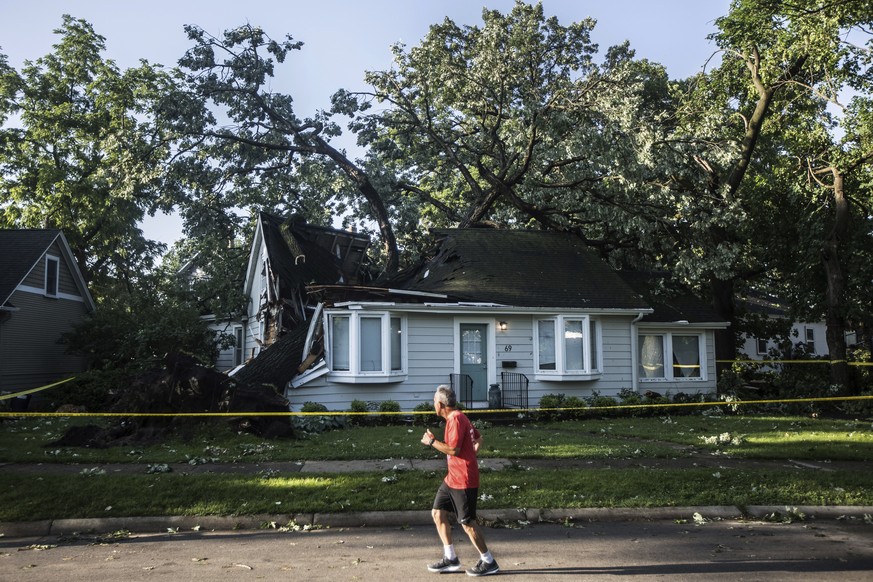 A person jogs past a large tree that fell into the roof of a home in Riverside during Monday evening&#039;s storm that raced across the Chicago area. A supercell thunderstorm with winds in excess of 8 ...