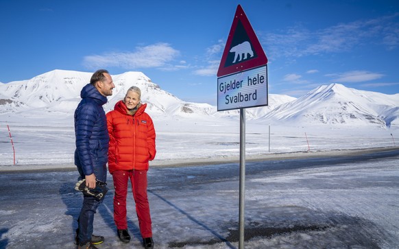 epa09900898 Crown Prince Haakon and Crown Princess Mette-Marit of Norway look at the sign warning of polar bears in Longyearbyen, Svalbard, Norway, 21 April 2022. The Crown Prince couple is on a count ...