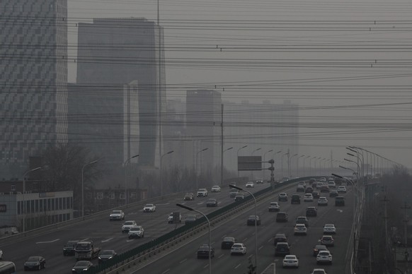 epa09717507 Vehicles run on a main road, with air pollution visible on the skyline, in Beijing, China, 30 January 2022. According to the Ministry of Ecology and Environment, the operations of some fac ...
