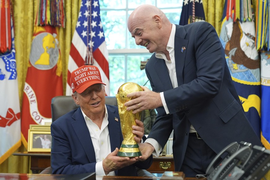 FIFA President Gianni Infantino, right, hands the FIFA World Cup Winners Trophy to President Donald Trump during an announcement in the Oval Office of the White House, Friday, Aug. 22, 2025, in Washin ...