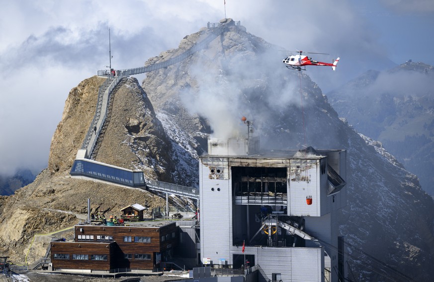 An helicopter carries water to stop an ongoing fire at the restaurant Botta at the Glacier 3000 resort in Les Diablerets, Ormont-Dessus, Switzerland, Monday, September 19, 2022. A fire broke out early ...