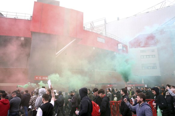 Fans make their way past barriers outside the ground as they let off flares whilst protesting against the Glazer family, owners of Manchester United, before their Premier League match against Liverpoo ...
