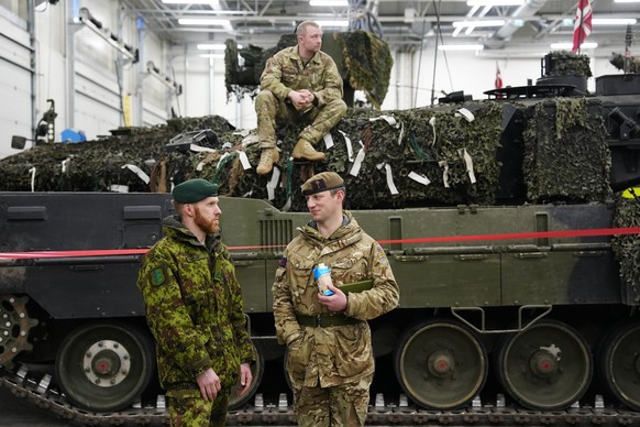 Un officier militaire danois assis sur un char Leopard 2A7, tandis que des officiers militaires britanniques et estoniens sont en pleine discussion au camp militaire de Tapa, en Estonie, jeudi 19 janv ...