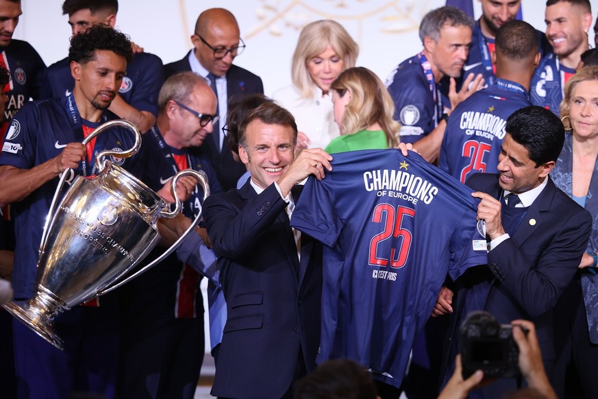 epa12149750 French President Emmanuel Macron (C) holds a PSG jersey “Champions of Europe 2025” with PSG president Nasser Al-Khelaifi (R) while PSG captain Marquinhos (L) carries the trophy during a re ...