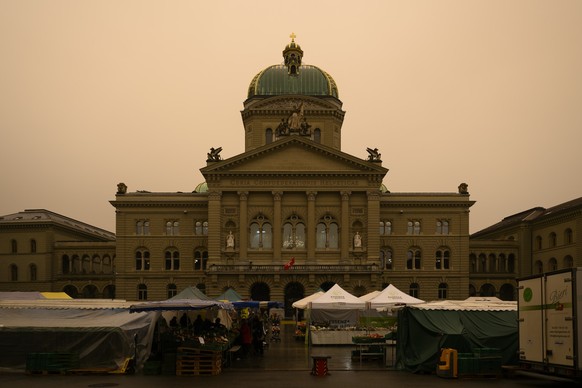 The Swiss Federal Palace is pictured in a special light atmosphere created by the Sahara sand that colours the sky in a yellow cast, in Bern, Switzerland, on Tuesday, 15 March 2022. (KEYSTONE/Anthony  ...