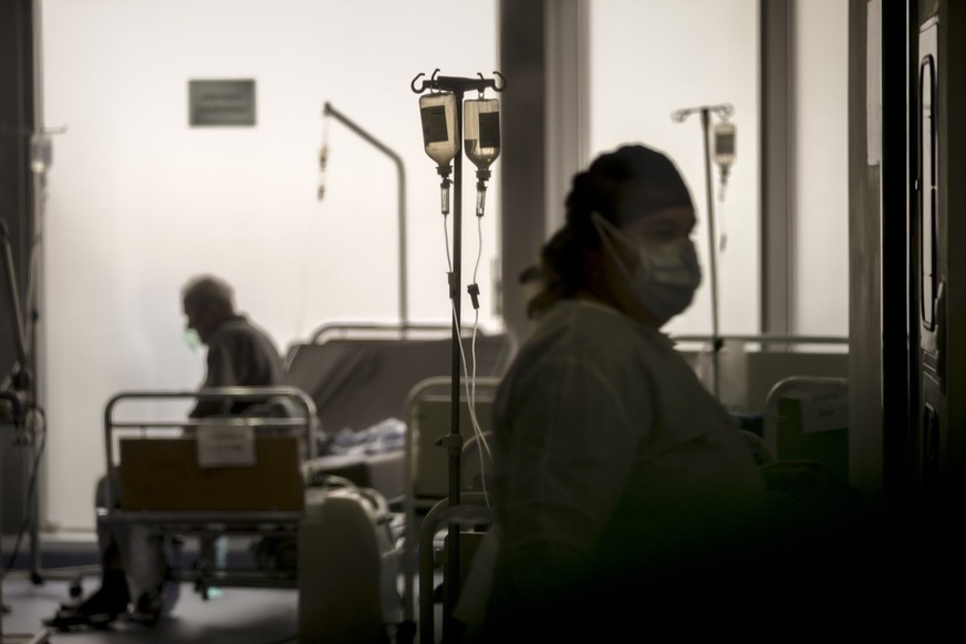 Seen through a plastic sheet a member of the medical staff checks on COVID-19 positive patients at the University Emergency Hospital waiting area, converted into a COVID-19 section due to the number o ...
