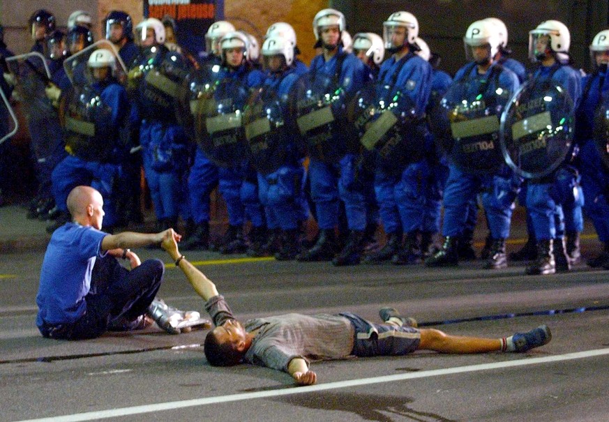 Two protesters lie and sit in front of a row of Zurich riot police in Geneva, Switzerland, late Monday, June 2, 2003. Demonstrators have gathered in Lausanne and Geneva over the last days to protest t ...