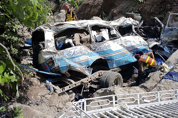 Rescue workers search for the victims and wounded passengers in the wreckage of a bus that fell into a ravine, near Kahuta, Pakistan, Sunday, Aug. 25, 2024. (AP Photo/Mohammad Yousaf)