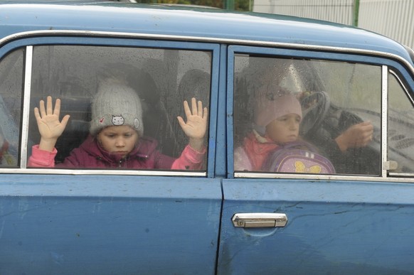 Children look through a car windows as they and other refugees from Kharkov Region of Ukraine come to temporary camp in Belgorod, Russia, Wednesday, Sept. 14, 2022. Thousands fled fled northeastern Uk ...