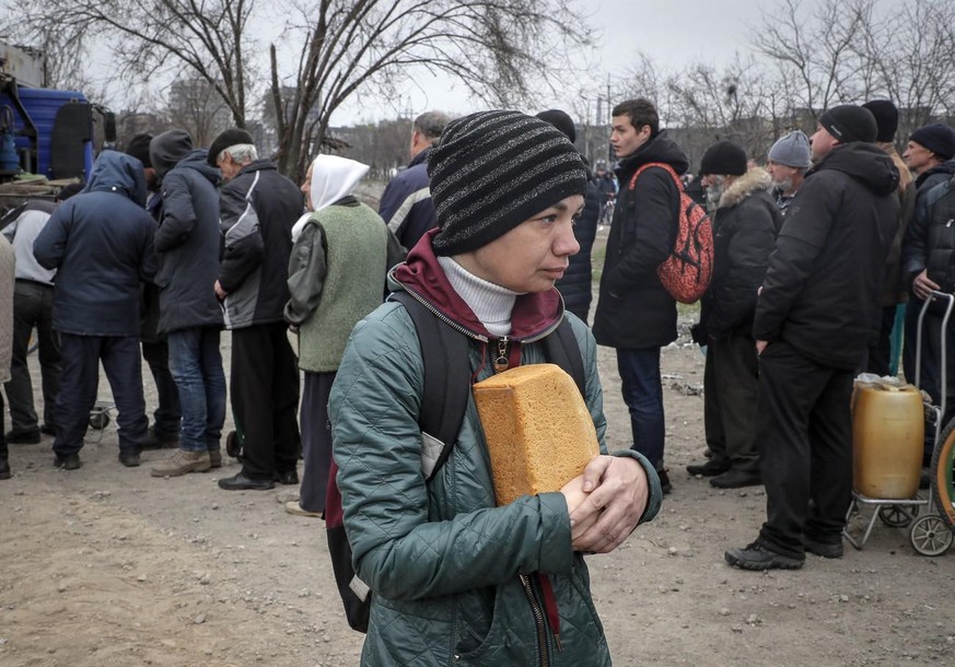 epa09886148 A picture taken during a visit to Mariupol organized by the Russian military shows a local woman holding breas as militias of self-proclaimed DPR distribute humanitarian aid to local peopl ...
