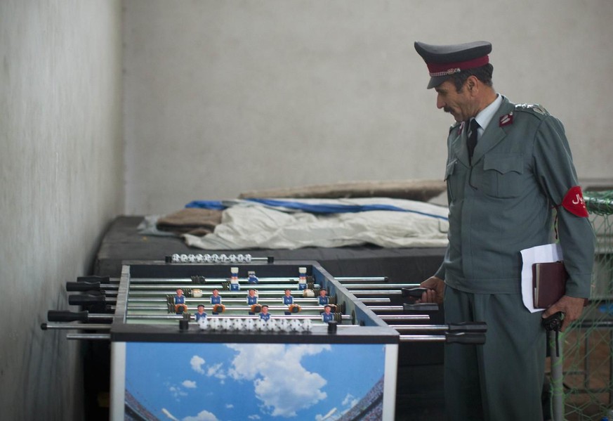 In this Tuesday, Oct. 9, 2012 photo, Afghan National Police Academy Director Maula Dad Pazoish tries out a table football in a recreation room at the police academy in Kabul, Afghanistan. &quot;The pe ...