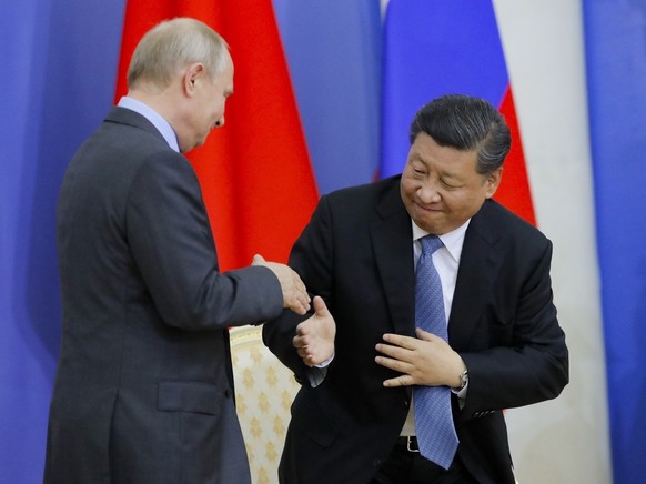 Chinese President Xi Jinping, right, and Russian President Vladimir Putin shake hands during the ceremony of presenting Xi Jinping degree from St. Petersburg State University at the St. Petersburg Int ...
