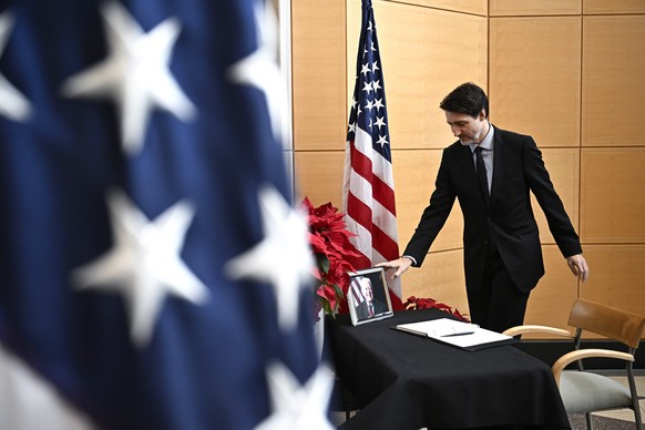 Prime Minister Justin Trudeau touches a photo of former U.S. President Jimmy Carter after signing a book of condolences at the U.S. Embassy in Ottawa, on Friday, Jan. 3, 2025. (Justin Tang /The Canadi ...