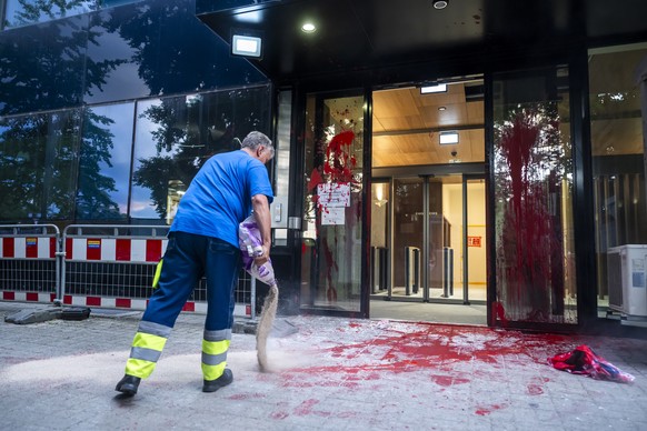 Un employe de la ville de Geneve jette du produit absorbant sur les degats suite a des manifestants propalestiniens qui ont lance de la peinture rouge sur la mission permanente d'Israel aupres de ...