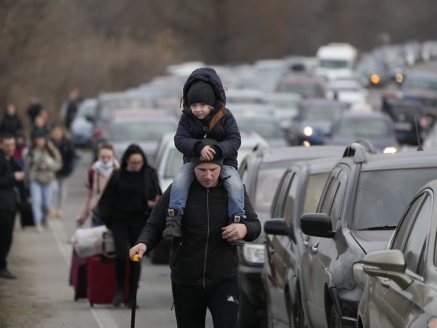 Des réfugiés ukrainiens marchant à côté de véhicules tentant de traverser la frontière entre l'Ukraine et la Moldavie.