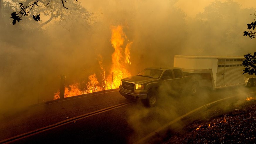 A livestock trailer drives along Canada Road as the Crews Fire burns near Gilroy, Calif., on Sunday, July 5, 2020. (AP Photo/Noah Berger)