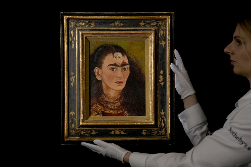 FILE - A staff member poses for photographs with the Mexican painter Frida Kahlo&#039;s 1949 self-portrait &quot;Diego y yo&quot;, Diego and I, at Sotheby&#039;s auction house in London, Thursday, Oct ...