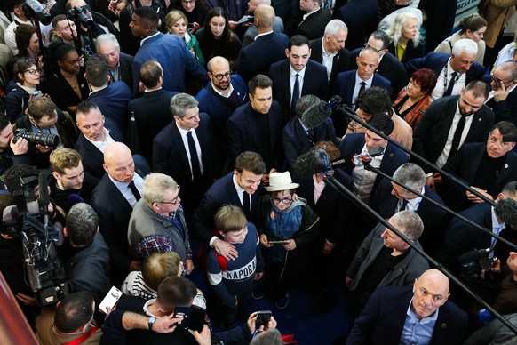 epa11915004 French President Emmanuel Macron poses with children during the opening day and inauguration of the 61st International Agricultural Fair (Salon de l&#039;Agriculture) at the Porte de Versa ...
