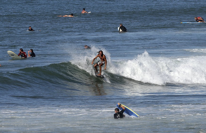 FILE - A surfer rides a wave in the Atlantic Ocean in Biarritz, southwestern France, Oct. 7, 2023. October was the fifth straight month that Earth set a record for the hottest month in recorded histor ...