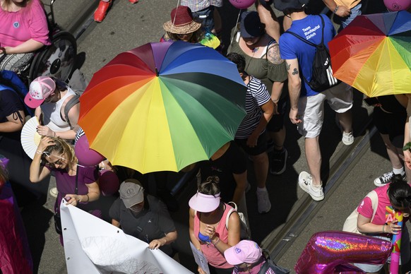 Teilnehmer der Pride schutzen sich mit Schirmen vor der Sonne, an der Zeurich Pride, fotografiert am Samstag, 20. Juni 2026 in Zuerich. (KEYSTONE/Christian Beutler)