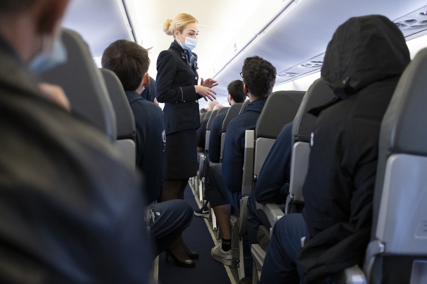 Flight attendant wearing a protective face mask speaks with passengers in an airplane of Bulgaria Air between Sofia in Bulgaria and Zuerich in Switzerland (Flughafen Zuerich) during the coronavirus di ...