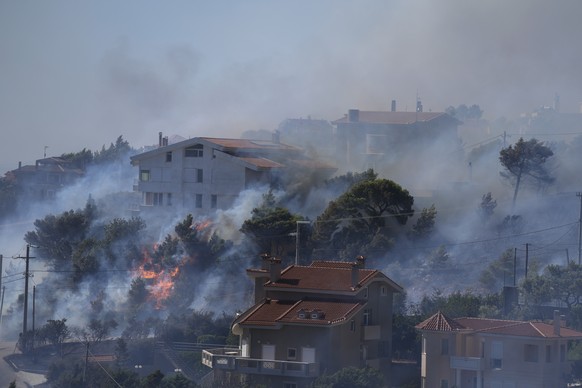 Fire burns next to houses in the area of Drafi east of Athens on Wednesday, July 20, 2022. Hundreds of people were evacuated from their homes late Tuesday as a wildfire threatened mountainside suburbs ...