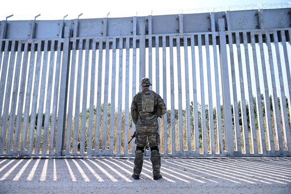 epa09440121 A soldier stands in front of a steel fence built along the Evros River in the area of Feres, at the Greek-Turkish border, Greece, 01 September 2021. The fence was built to prevent the ille ...