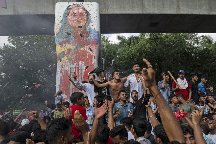 FILE - Protesters celebrate beside a defaced portrait of Prime Minister Sheikh Hasina after news of her resignation, in Dhaka, Bangladesh, on Aug. 5, 2024. (AP Photo/Fatima Tuj Johora,File)