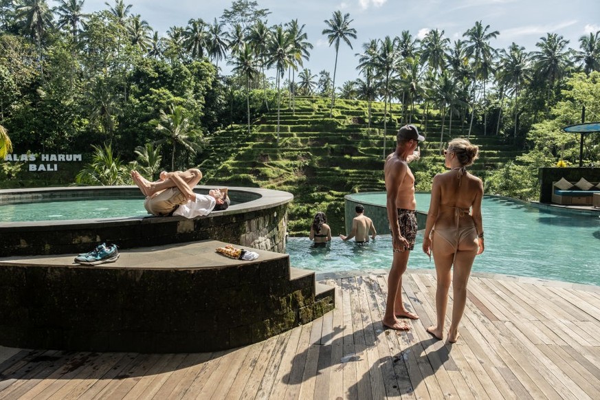 UBUD, BALI, INDONESIA - DECEMBER 8: Foreign tourists use a swimming pool with a rice terrace in the background on December 8, 2022 in Ubud, Bali, Indonesia. Indonesia's parliament voted to pass a ...