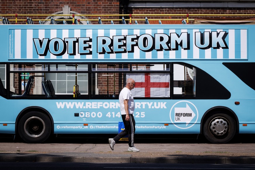 epa13150080 A person walks past a Reform UK campaign bus outside Clacton station in Clacton-on-Sea, Essex, Britain, 04 August 2026. Reform UK leader Nigel Farage will contest the Clacton by-election o ...