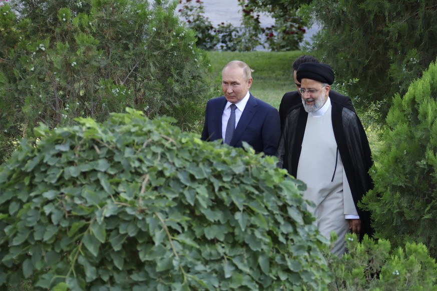 In this photo released by the official website of the office of the Iranian Presidency, Russian President Vladimir Putin, left, and his Iranian counterpart Ebrahim Raisi walk at the presidency palace  ...