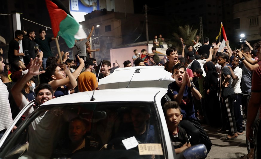 Palestinians chant slogans as they wave their national flags while celebrating the cease-fire agreement between Israel and Hamas in Gaza City, early Friday, May 21, 2021. (AP Photo/Adel Hana)