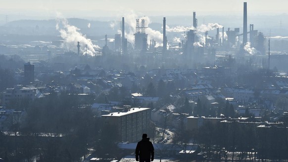 A man watches a steaming BP refinery in the city of Gelsenkirchen, on a frosty but sunny winter Tuesday, Jan. 19, 2016. Millions of customers benefit from the low heating oil prizes this winter. (AP P ...