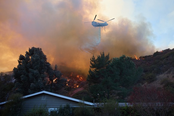 epaselect epa11819202 A helicopter does a water drop over a home during the Palisades wildfire in Los Angeles, California, USA, 11 January 2025. Thousands of firefighting and emergency personnel are i ...