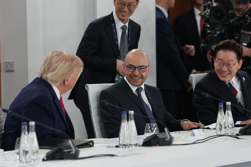 U.S. President Donald Trump talks to CEO of Google DeepMind Demis Hassabis, center, and South Korea's President Lee Jae Myung as they participate in a meeting with leaders during the G7 summit, W ...