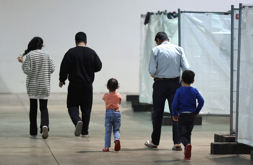 epa11030995 A refugee family walks at an emergency accommodation for asylum seekers at the fair in Offenburg, Germany, 15 December 2023. Offenburg&#039;s exhibition center provides space for up to 400 ...