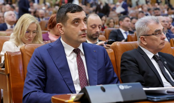 epa12933860 Ultra-nationalist Alliance for the Union of Romanians (AUR) party leader George Simion (L) listens to Romania's Prime Minister Ilie Bolojan's (not pictured) speech before a no-co ...