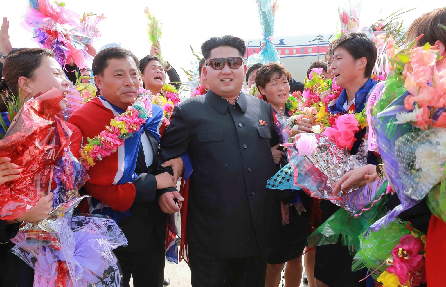 epa04879599 North Korean leader Kim Jong-un (C) greets members of the North Korean women's national soccer squad at Pyongyang International Airport, North Korea, 10 August 2015, in this photo ...