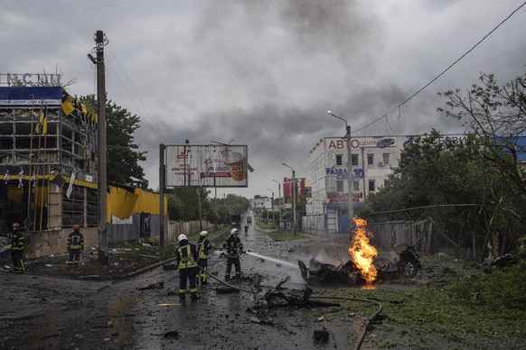Rescue workers put out the fire of a destroyed car after a Russian attack in a residential neighborhood in downtown Kharkiv, Ukraine, on Monday, July 11, 2022. The top official in the Kharkiv region s ...