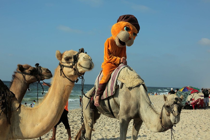 A Palestinian dressed as a clown leads a camel at the beach in Gaza City on August 10, 2016.
(Photo by Majdi Fathi/NurPhoto via Getty Images)