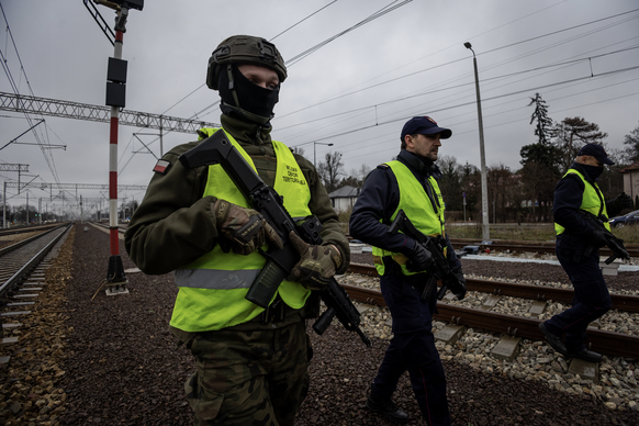 Des gardes de la sécurité ferroviaire et un soldat des forces de défense territoriale patrouillent le long des voies ferrées dans la banlieue de Varsovie, en Pologne, le 27 novembre 2025.