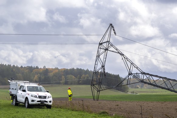 Two employees of the Romande Energie company is work on an electricity pylon is seen on the ground after being knocked down by strong winds during the autumn storm, Benjamin, in Biere, Switzerland, Th ...