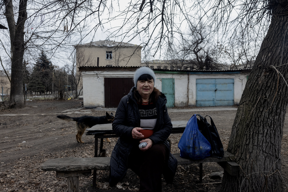 Raisa, assise sur un banc, est entourée de chiens errants dans la ville de Bilytske, dans la région de Donetsk, le 13 mars 2025, au moment de l&#039;invasion russe de l&#039;Ukraine. Il était dix heur ...