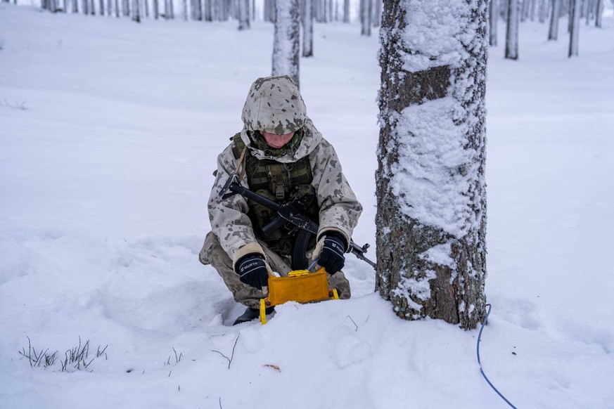 Un conscrit installe une mine antipersonnel dans la forêt enneigée.