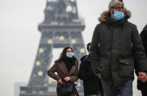 epa09680488 Pedestrians wearing face masks walk near the Eiffel Tower in Paris, France, 12 January 2022. COVID-19 cases have recorded its highest number daily since the start of the pandemic in France ...