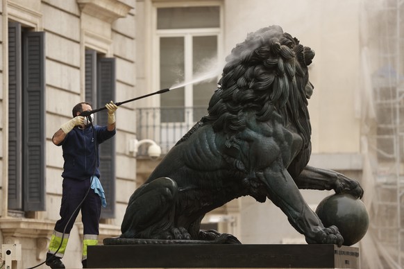 epa09826090 A worker cleans the sculptures of a lion outside the Congress of Deputies after dust from the Sahara desert swept through southern and central Spain propelled by storm Celia, in Madrid, Sp ...