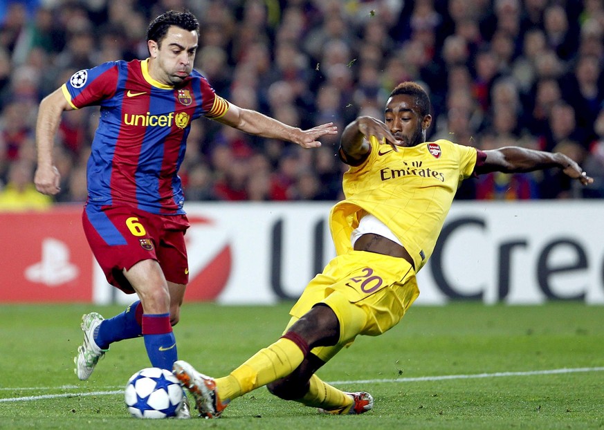 epa02622517 Arsenal FC's Swiss defender Johan Djourou (R) vies for the ball with FC Barcelona midfielder Xavi Hernandez (L) during the UEFA Champions League round of 16 soccer match at the Camp N ...