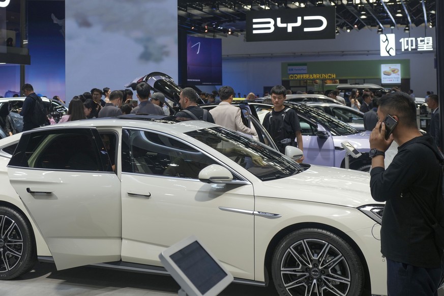 FILE - Visitors look at cars at the BYD booth during the China Auto Show in Beijing, China, Friday, April 26, 2024. The European Union threatened on Wednesday, june 12, 2024, to hike tariffs on Chines ...