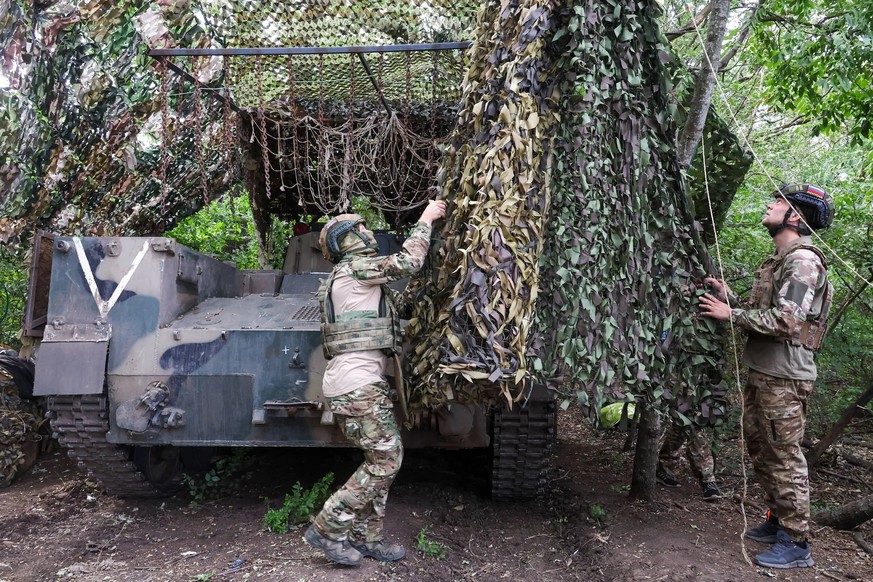 Des soldats russes recouvrent un véhicule blindé de transport de troupes BMD d&#039;un filet de camouflage (photo d&#039;archive): on peut également voir sur le véhicule des dispositifs de protection  ...